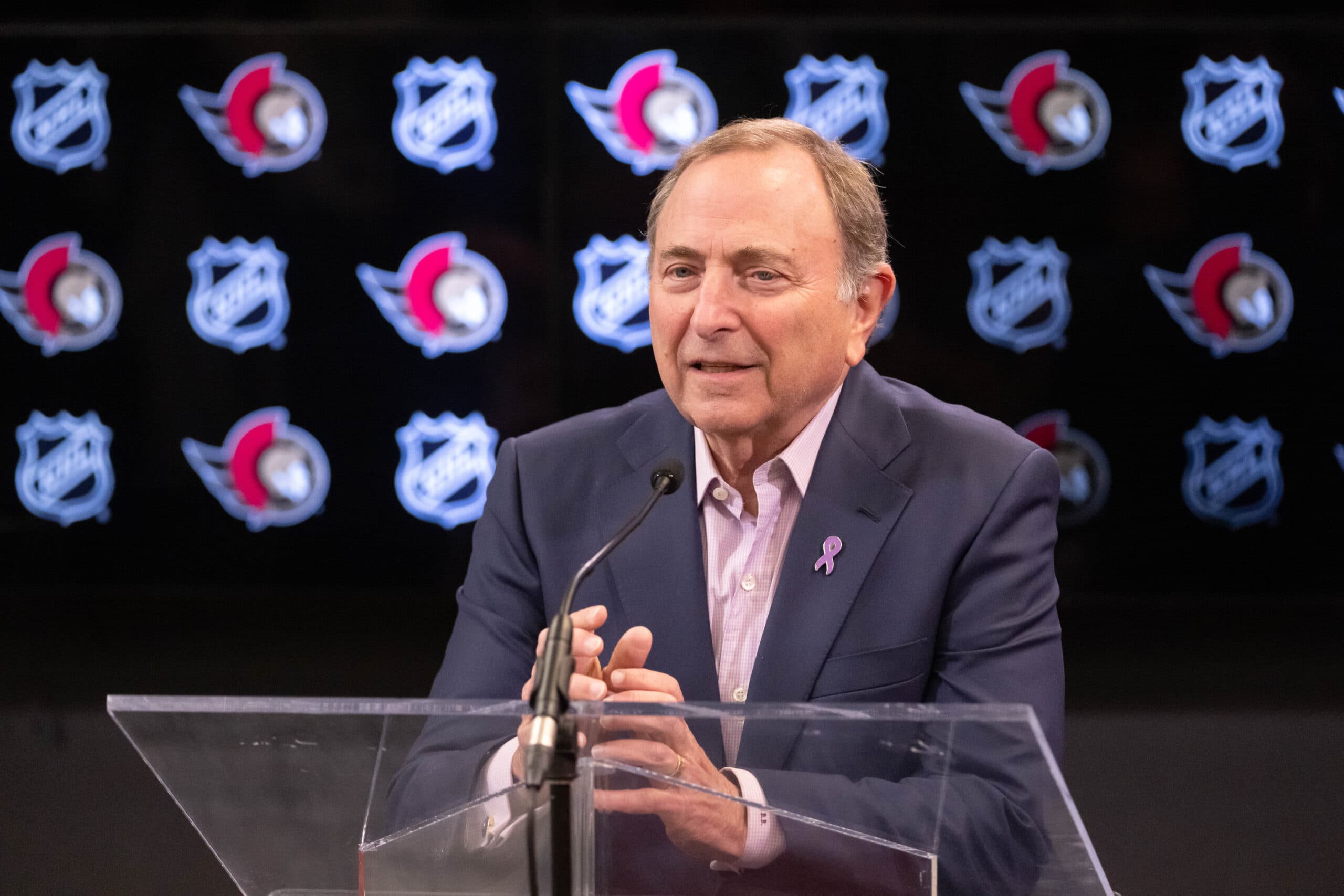 Gary Bettman sits at a podium speaking